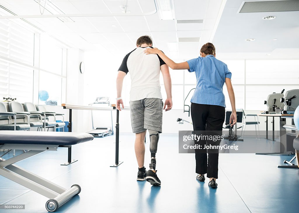 Physiotherapist helping young man with prosthetic leg