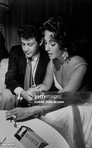 Singer Eddie Fisher holding hands w. His actress fiancee Elizabeth Taylor who is sporting a 50-diamond bracelet he gave her as an engagement present...