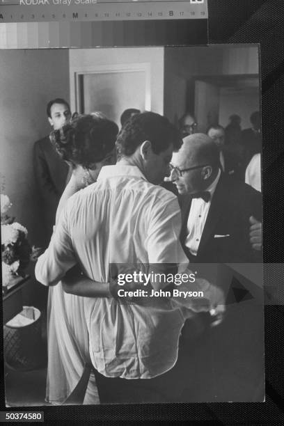 Singer Eddie Fisher w. Shirt tail hanging out & an arm around his actress fiancee Elizabeth Taylor as he is congratulated in his dressing room after...