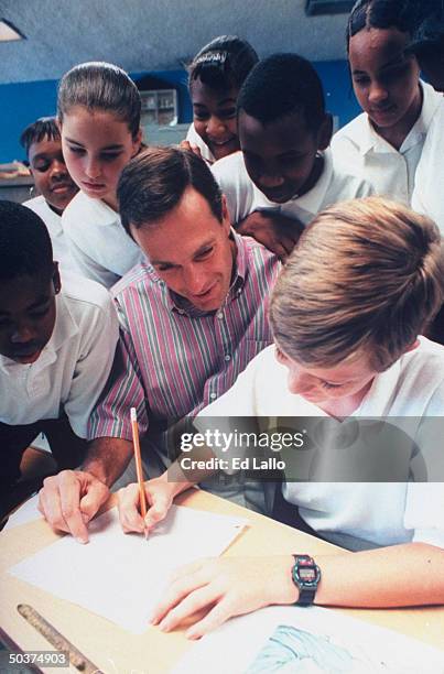 Algebra teacher Tom Bloch, former CEO of H&R Block, working w. Students at desk in ST. Francis Xavier middle school.