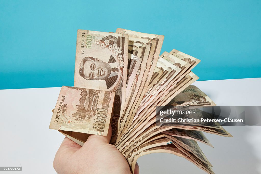 Holding a handful of 5000 North Korean Won banknotes