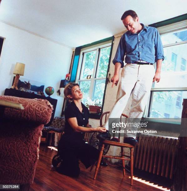 Humorist/writer David Sedaris is standing on chair as his sister Amy adjusts the hem on his pants, at his apt.