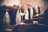 Glass of White Wine on a Barrel in Wine Cellar