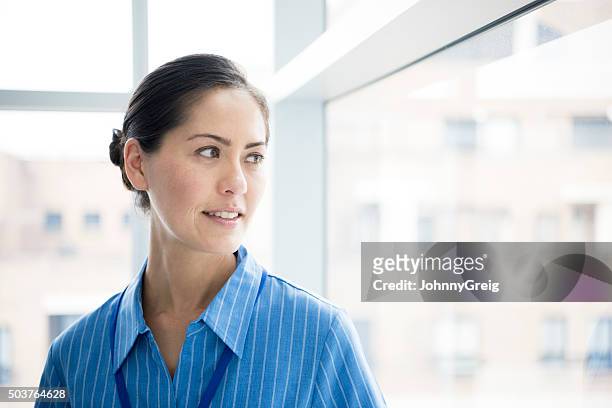 candid portrait of asian nurse looking through window - nurse thinking stock pictures, royalty-free photos & images