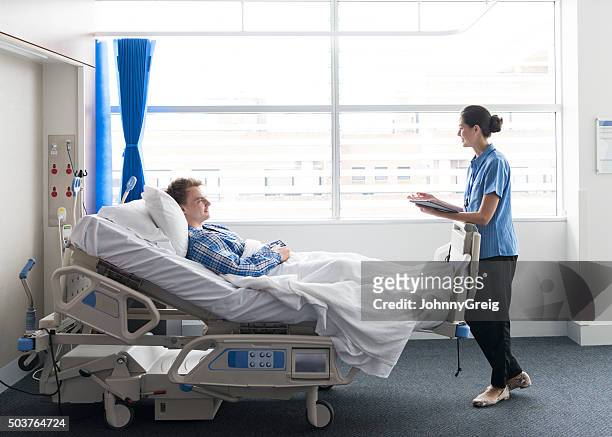 young man lying in bed in hospital with female nurse - bedside table stock pictures, royalty-free photos & images