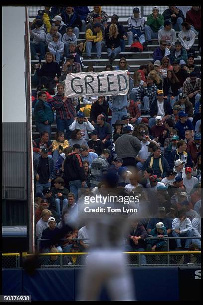 View of fan in stands holding up sign that reads GREED during Chicago White Sox vs Milwaukee Brewers game.