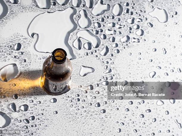 bottle of empty beer on a wet surface - bottle condensation stock pictures, royalty-free photos & images