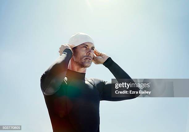 triathlete in a wetsuit putting on a swimming hat - determination stock pictures, royalty-free photos & images