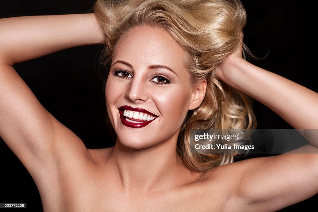 Glamorous Woman Smiling with Hands in Blond Hair