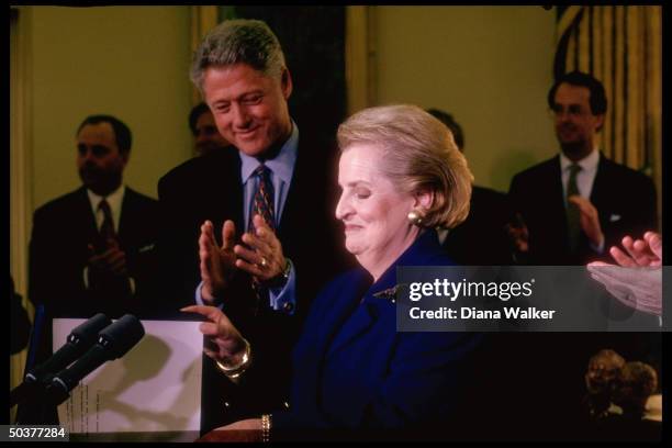 State Secy. Madeleine Albright smiling as Pres. Bill Clinton applauds during her swear-in ceremony in White House Oval Office.