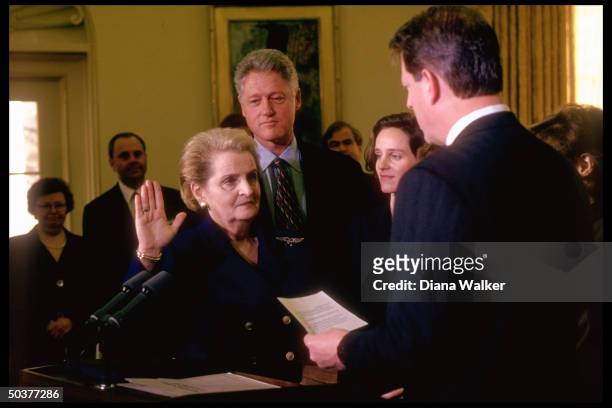 State Secy. Madeleine Albright raising hand, being sworn-in by VP Al Gore w. Her daughter & Pres. Bill Clinton in witness, in White House Oval Office...