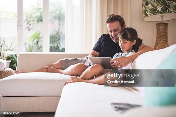 watching funny videos with her dad - australian family home stockfoto's en -beelden