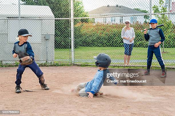 brothers playing baseball, one sliding to the plate mom watching. - baseball mom stockfoto's en -beelden