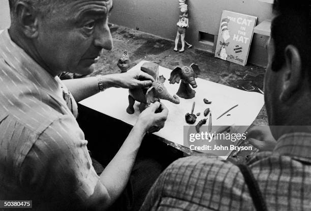 Children's book author/illustrator Theodor Seuss Geisel working on clay models of some of the characters he has created.