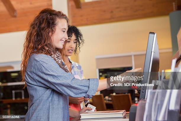 college age customers using self check out in public library - bod bildbanksfoton och bilder