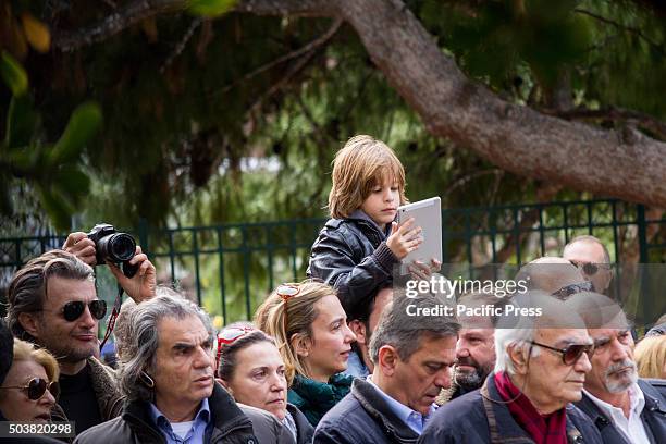 Young boy sits on his father's shoulders filming the ceremony with an iPad. Epiphany holiday celebrated with the sanctification of the waters. Prime...