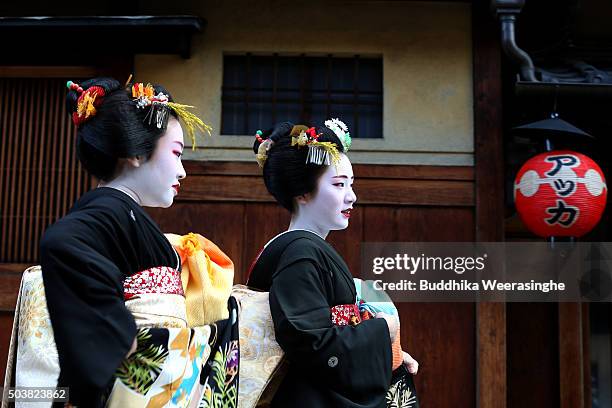 Japanese traditional female dancers, maikos, and performers, geikos walk in the street during the new year's ceremony at the Gion Kobu Kaburenjo...