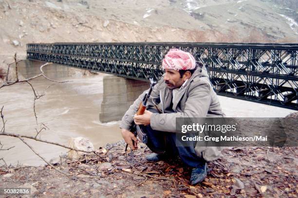 Kurdish peshmerga soldier armed with an AK-47 guarding a bridge fr. Possible attack fr. Iraqi troops during the cold winter months in the mountains...