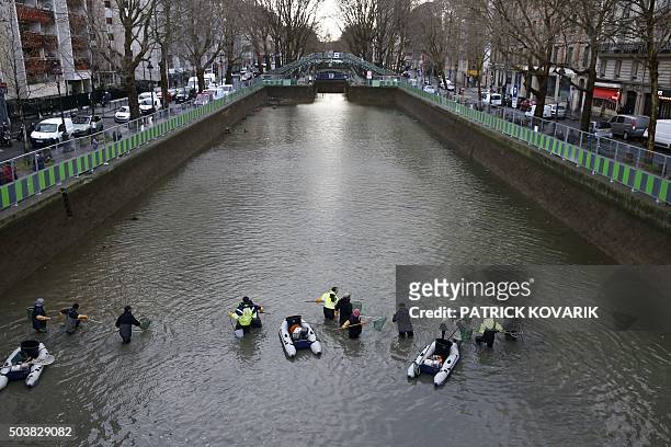 Workers remove fish from the canal Saint Martin in Paris on January 7, 2016 before a drainage and cleaning operation. / AFP / PATRICK KOVARIK