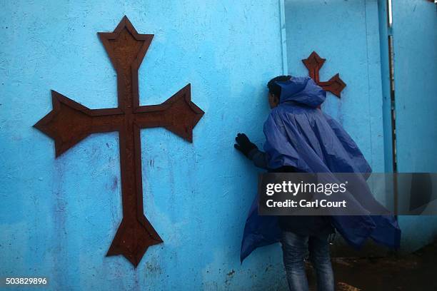 An Eritrean Orthodox Christian kisses a gate as he arrives to attend a Christmas service at a church in the camp known as 'The Jungle' on January 7,...