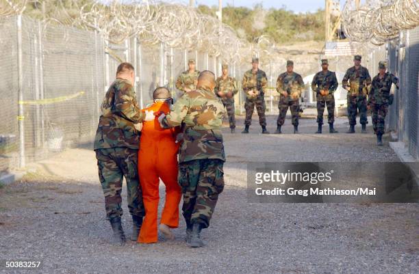 Army military police escorting Taliban prisoner to his cell in Camp X-Ray at Naval Base Guantanamo Bay, Cuba, during in-processing to the temporary...