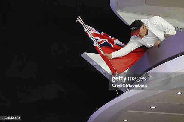 An employee places a sailing Union Jack flag on to the back of a Sunseeker International Ltd boat at the ExCel exhibition centre in preparation for...