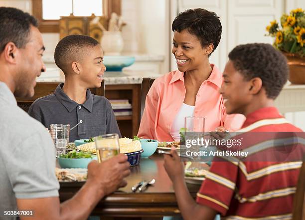 black family eating dinner together - social grace stock pictures, royalty-free photos & images