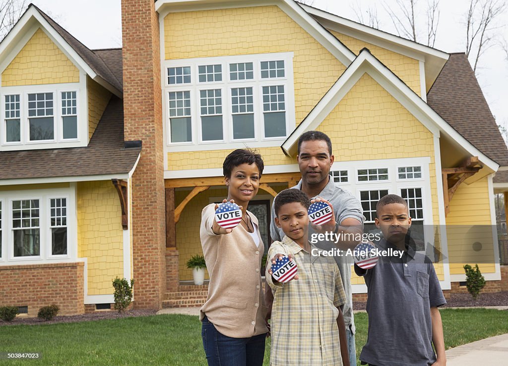 Black family holding Vote buttons outside home