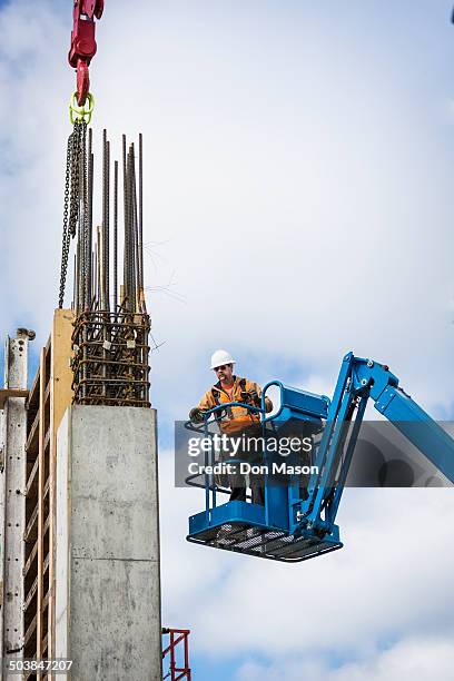 caucasian worker standing on boom lift on site - cherry picker stock pictures, royalty-free photos & images