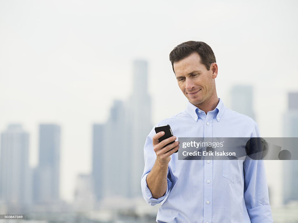 Caucasian businessman using cell phone on urban rooftop