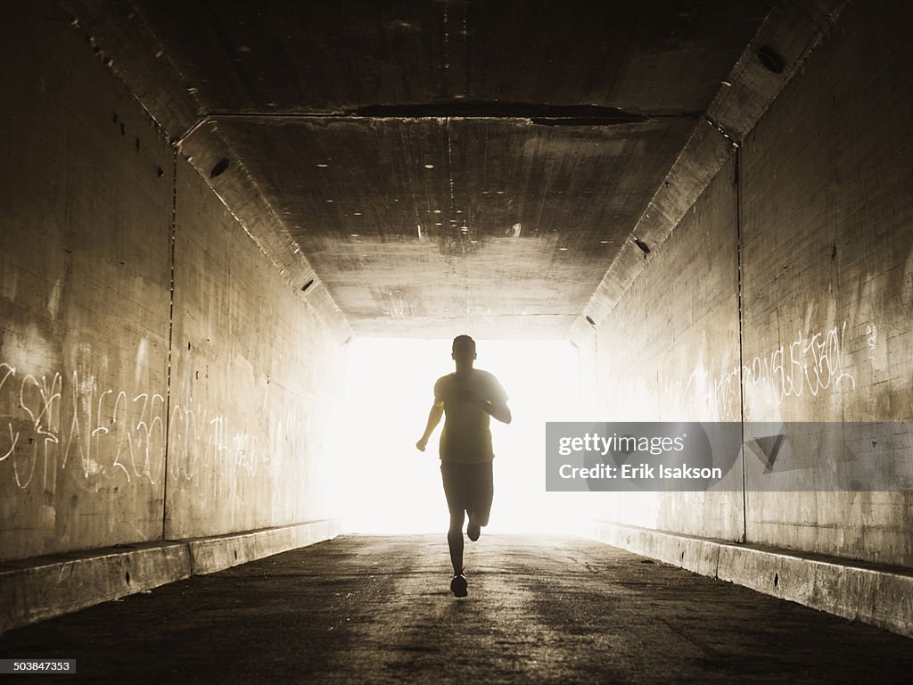 Caucasian man running in urban tunnel