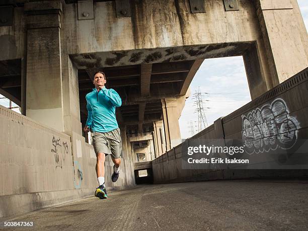 caucasian man running in urban tunnel - graffiti hintergrund stock pictures, royalty-free photos & images