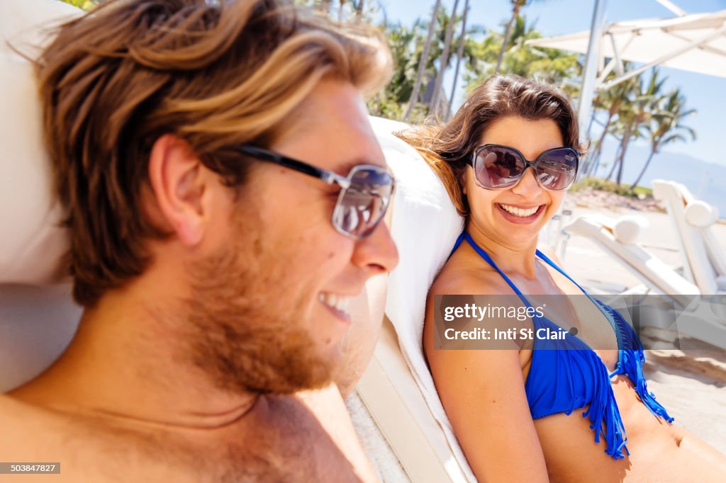 Couple relaxing in lounge chairs on beach