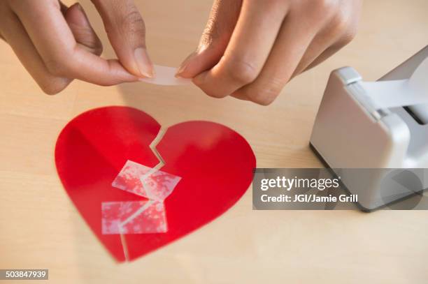 mixed race woman taking broken paper heart - cuore spezzato foto e immagini stock