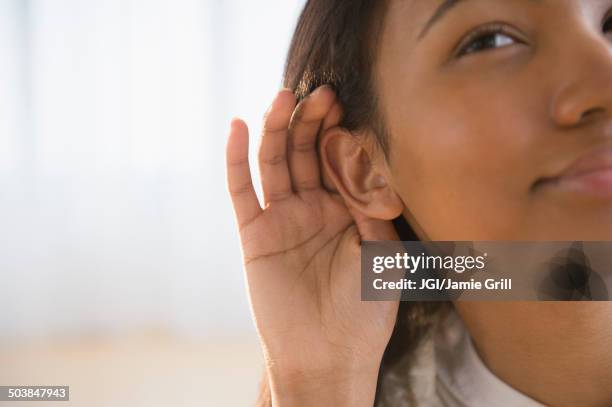 mixed race woman cupping her ear - hands cupped stock pictures, royalty-free photos & images