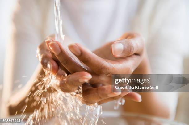 mixed race woman washing her hands - washing hands photos et images de collection