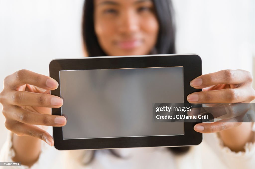 Mixed race woman holding digital tablet