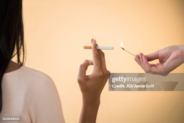 man lighting woman's cigarette - femme et fumeuse photos et images de collection