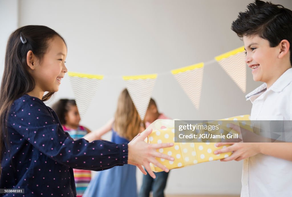 Boy giving girl birthday present at party