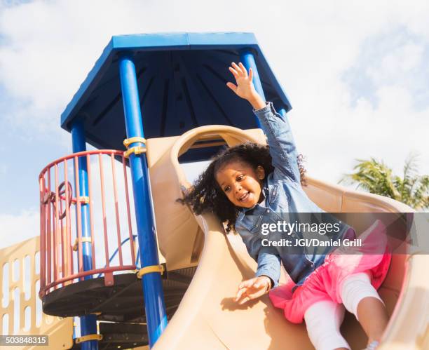 mixed race girl playing on playground - área de juego fotografías e imágenes de stock