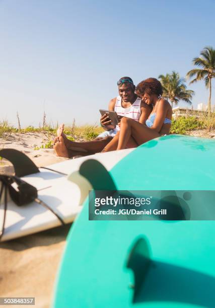 couple using digital tablet on beach - surfer sur le net fotografías e imágenes de stock