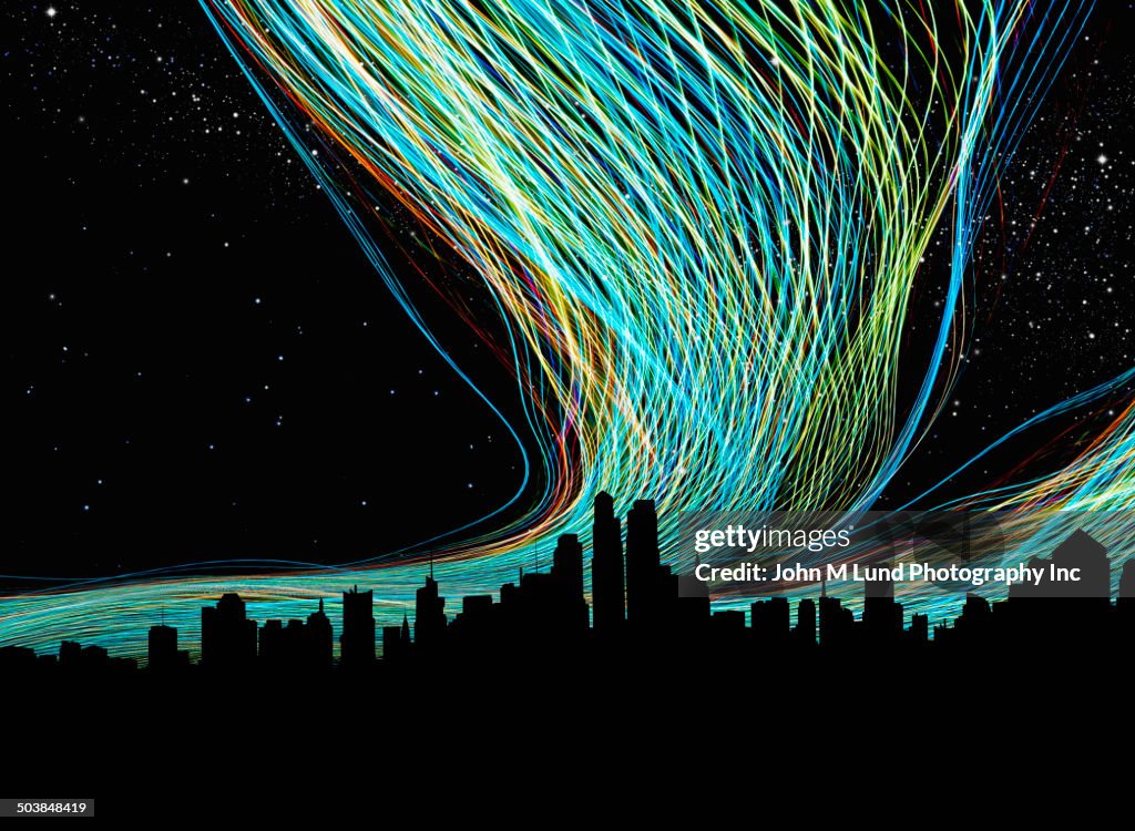 Light trails over silhouette of city skyline