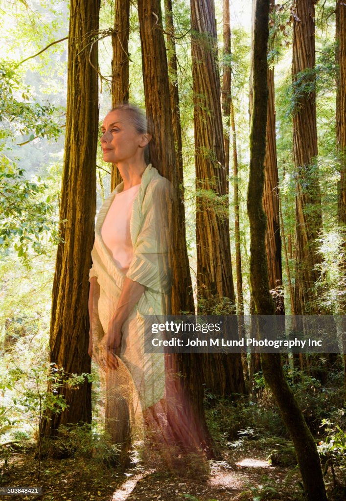 Ghostly Hispanic woman standing in forest