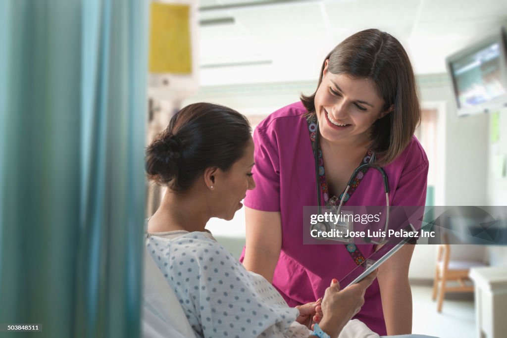 Nurse using digital tablet with patient in hospital