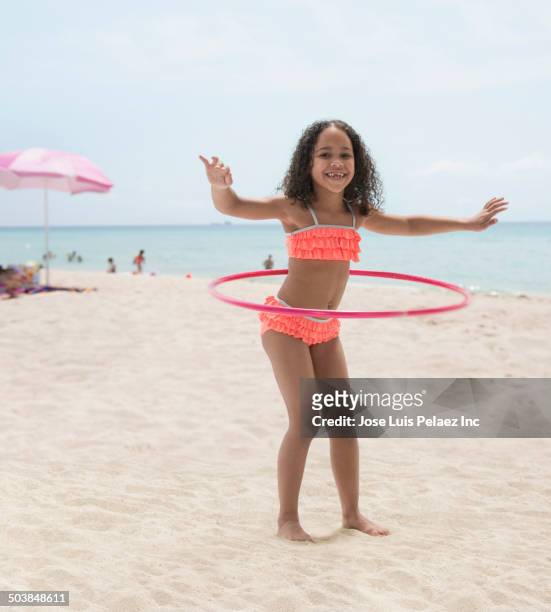 mixed race girl hula hooping on beach - fille maillot photos et images de collection