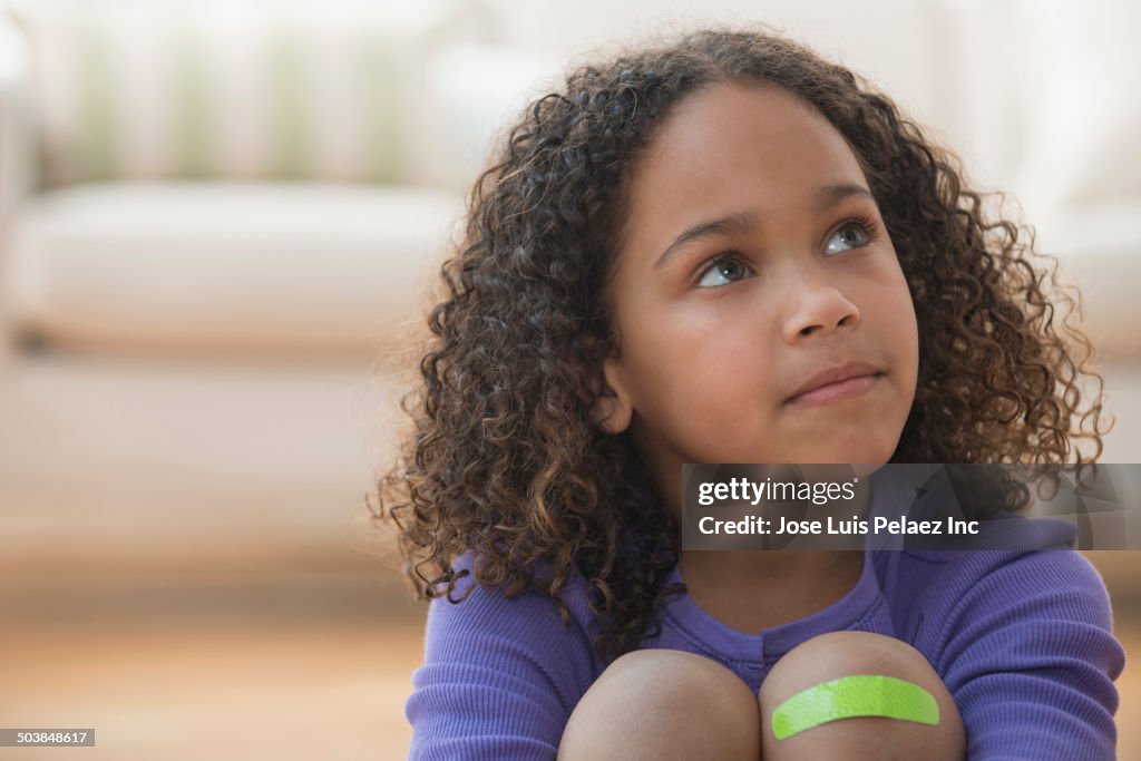 Mixed race girl wearing bandage on knee