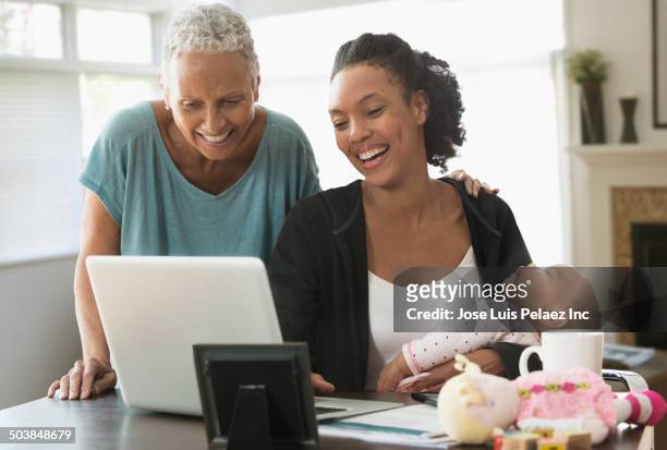 three generations of women using laptop at desk - grandma sleeping stockfoto's en -beelden
