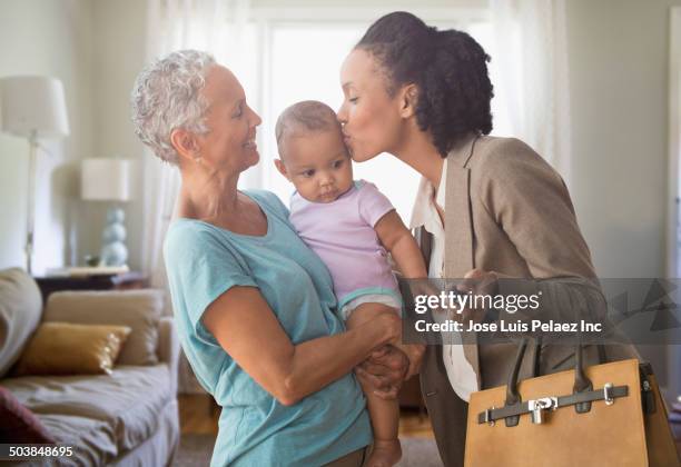 mother working while grandmother plays with baby - working mother stock pictures, royalty-free photos & images