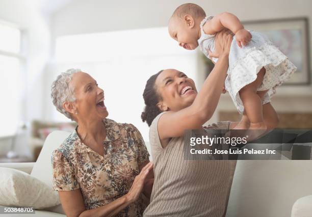 three generations of women playing on sofa - multi generation family stock pictures, royalty-free photos & images