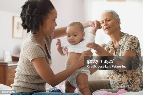 woman and mother caring for baby - help getting dressed stock pictures, royalty-free photos & images